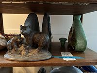 Photo of ceramic statue with two bears standing on a textured base, showing details and size relative to shelf.