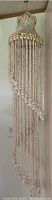Full view of the longest shell chandelier, showing long strands of white shells and a spiral pattern