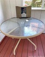 Top view of round patio table with textured tempered glass top and Audiovox CD and radio music player placed on it