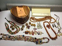 Overview of all jewelry and wooden heart-shaped box displayed on a white surface showing variety of necklaces, earrings, pins, bracelets, and hair combs.