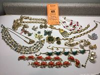 All displayed costume jewelry items including pins, necklaces, bracelets, and earrings with various motifs such as butterflies, fish, turtle, and bird in predominantly gold-tone metal and colorful accents.
