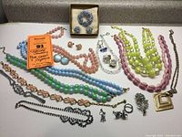 Various beaded and crystal jewelry including pink, green, blue, and yellow necklaces, clip on earrings, bracelets, and brooch.