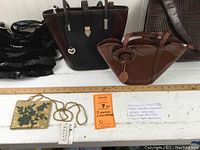 Five purses displayed on a white bench with measuring ruler, showing various styles and colors including black, brown, and sequin bead dressy purse.