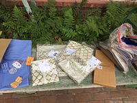 Photo showing clear garment bags, patterned under bed storage bags, folded blue fabric items, and small accessories on a bench.