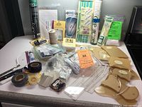 Overview of various quilting supplies including rulers, spools of thread, adhesive tapes, pins, and templates on white counter.