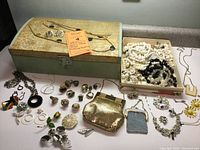 Full view of the assortment displaying the two mesh bags, costume jewelry, and vintage box on a flat surface