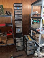 Photo showing two tall black plastic storage drawer units containing vinyl letters, stencils, stickers, and various airbrush related craft supplies.