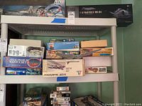 Shelf filled with various opened model kit boxes including airplanes and ships.