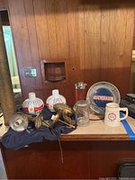 Brass wall sconces with Budweiser glass shades plus glass mug, metal bar shaker, ceramic stein and Schlitz clock in background.