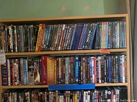 Two wooden shelves filled with a variety of DVDs, showing mostly full rows of DVD cases aligned vertically.