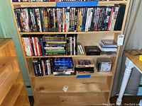 Three shelves with DVDs arranged in a bookshelf, showing multiple titles and boxed sets.