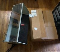 Fold-up spray booth and packing box on wooden floor, showing the overall form and condition of the booth.