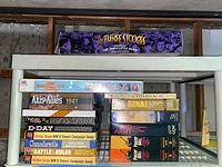 Shelf view of assorted board game boxes including The Three Stooges, Babysitters Club, Axis & Allies 1941, Cribbage, Sinai, Red Army, Panzer Blitz
