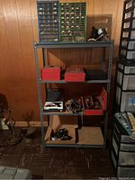 Full view of one metal storage shelving unit filled with a mix of toolboxes, parts organizers, and hardware items.