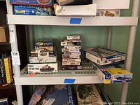 Shelf display of military miniatures and tank model kits with mostly opened boxes.