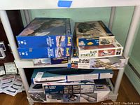 Five boxed model kits stacked on shelves showing Sherman Tank, B-47E Stratojet, and B-24D Liberator among others.