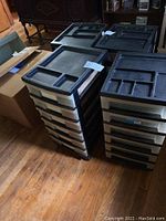 Two black and white multi-drawer storage containers on wooden floor.