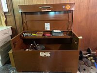 Open brown Knaack Jobmaster 69 tool chest showing contents including assorted hand tools, plastic box, and metal bucket inside.