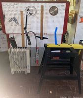 Overall view of the lot showing heater, tools on pegboard, plastic sawhorses, and metal stand on floor