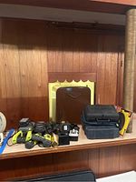Wide shot showing all tools, batteries, chargers, and Dremel case on a wood surface against a wood-paneled wall