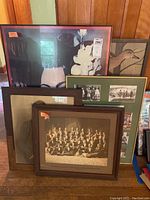 Five framed artworks arranged on the floor showing different sizes and styles, including class photos and waterfowl art.