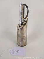 Front angled view of the letter opener with cylindrical silverplate base and blade upright.