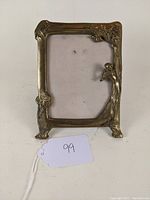 Full frontal view of the Art Nouveau brass or bronze picture frame showing the rectangular shape with figural female and floral accents.
