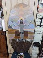 Full view of cubist religious painting on oval board showing stylized figure with raised arms and geometric background.