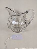 Side view of clear glass jug with Puritan pattern showing rounded ridges and curved spout.