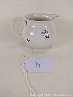 Side view of vintage Royal Doulton ceramic pitcher showing floral decoration and handle.