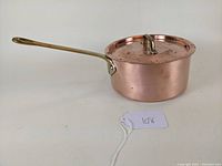 Side angle view of French copper saucepan with fitted lid and brass handle, showing pot and lid clearly.