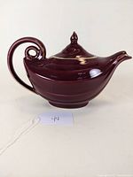 Side view of the purple Hall China Aladdin style ceramic teapot showing the lid, curved handle, and spout.