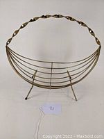 Front view of the mid century brass wire fruit basket showing twisted handle and wire design.