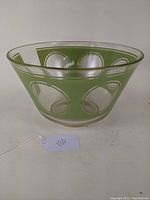 Large glass salad bowl with green reverse polka dot design, angled view showing shape and detailing.