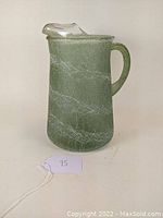 Front view of green textured glass pitcher with clear rim and handle, showing crackled spaghetti surface and spout.