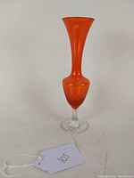 Front view of the tangerine orange glass bud vase with flared narrow top and clear pedestal base.