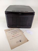 Front view of the RCA Victor bakelite phonograph with the original instruction manual placed in front.