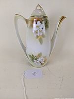 Front view of porcelain coffee pot with floral design and lid in place