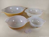 Set of four Pyrex Cinderella mixing bowls in Golden Butterfly pattern placed together showing size variety