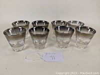 Front view of 8 clear double old fashioned tumblers with silver fade rims arranged in two rows, showcasing the rounded shape and silver gradient.