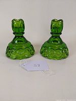 Front angle view of pair of green glass candlesticks with Moon & Stars pattern showing shape and embossed detail.