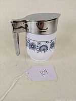 Side view of the Pyrex creamer showing the metal handle, spout and Old Town blue floral pattern.