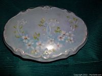 Top view of larger oval ceramic dish with raised floral white and yellow flowers on a blue background showing embossed details