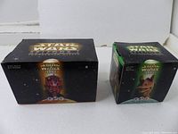 Two boxed Star Wars Episode 1 toys from 1999 placed side by side on a white surface, showing front and top of boxes.