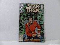Front cover of Star Trek comic book issue #51 with character in red uniform and green faces in background.