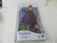 Front view of the blister pack showing Anna doll with Grand Pabbie doll inside, Disney Frozen 2 branding and Hasbro logo visible.