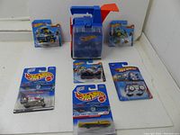 Shot of the Hot Wheels carry case and six Hot Wheels cars in original packaging displayed out of the case on a white surface.