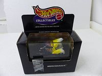 Front and top view of the Hot Wheels Mercohaulic die-cast model car in original black display case showing flame decals and chrome engine.