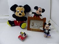 Mickey Mouse plush toys, wooden photo frame, and red car figurine with Mickey and Minnie Mouse