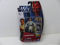 Front view of Star Wars Obi-Wan Kenobi MH08 action figure in sealed original packaging showing the clear blister pack and printed cardboard backing with character and branding details.